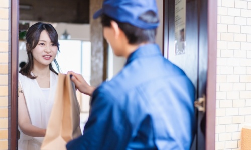 女性に荷物を届ける配達員